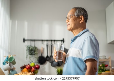 Asian senior mature male drinking a glass of water in kitchen at home. Attractive elderly older grandfather holding clean mineral natural in cup and sleeping in morning for health wellbeing in house.
 - Powered by Shutterstock