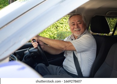 Asian Senior Men Driving A Car And Smile Happily With Glad Positive Expression During The Drive To Travel Journey, People Enjoy Laughing Transport And Relaxed Happy Mature Man On Roadtrip Concept