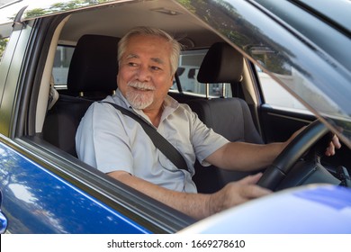 Asian Senior Men Driving A Car And Smile Happily With Glad Positive Expression During The Drive To Travel Journey, People Enjoy Laughing Transport And Relaxed Happy Mature Man On Roadtrip Concept