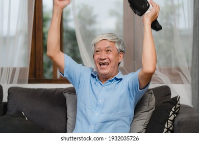 Asian Senior Men Play Games At Home. Asian Senior Older Chinese Male Happy Fun And Virtual Reality, VR Playing Games While Lying Sofa In Living Room At Home Concept.