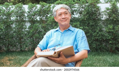 Asian Senior Men Relax At Home. Asian Senior Chinese Male Enjoy Rest Time Wear Glasses Read Books While Lying In The Garden At Home In The Morning Concept.