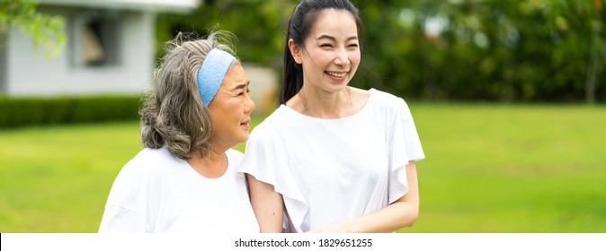 Asian Senior Mother And Adult Daughter Holding Hands And Exercise Walking Outdoor At  Park. 