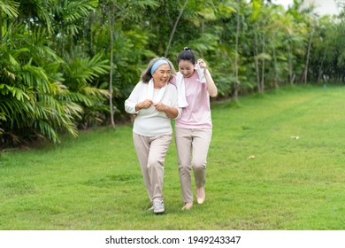 Asian Senior Mother And Adult Daughter Holding Hands And Exercise Walking Outdoor At  Park. 