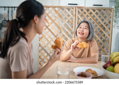 Asian Senior Mother Having Breakfast And Talking With Daughter At The Tablet. Asia Family Enjoy Eating Together.