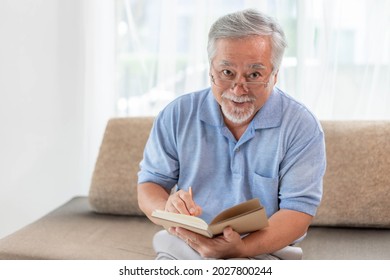 Asian Senior Old Man With Eye Glass Reading Novel Book , Smiling Feel Happy On Sofa At Home - Lifestyle Senior Elderly People Concept