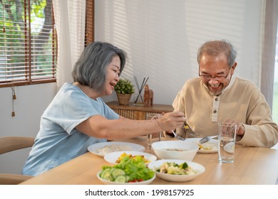 Asian Senior Older Couple People Eat Food On Dinner Table In House. Loving Elderly Mature Smile, Enjoy Retirement Life Having Breakfast In Morning Together At Home. Healthy Food And Insurance Concept.