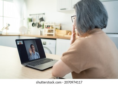 Asian senior older woman video call with doctor in living room at home. Elder patient consulting with general practitioner application computer laptop. Doctor and Consultant online and telemedicine. - Powered by Shutterstock