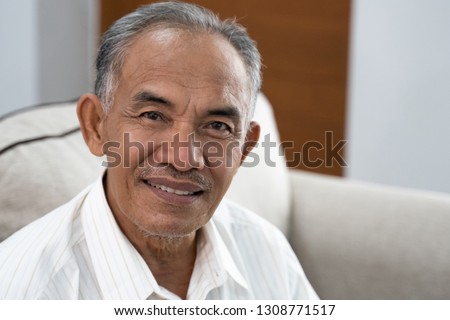 asian senior oldman sitting on the sofa smile when look at the camera