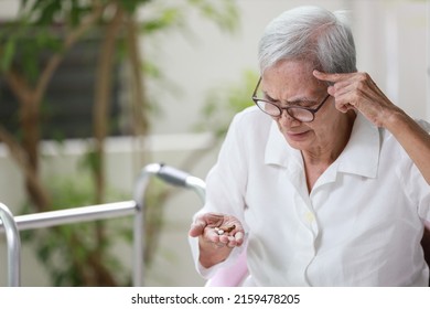 Asian senior patient with Alzheimer's disease or dementia,look at the pills capsules on her palm,trying to think,confused,old elderly people forget to take the medication,fail to remember or amnesia - Shutterstock ID 2159478205