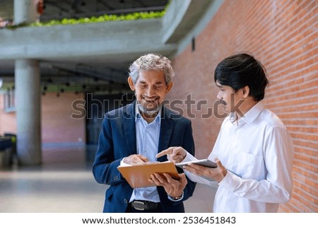 Asian senior professor is giving advice  to the college student on the research thesis while sitting in the university faculty for education, academic and business
