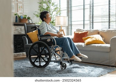 asian senior retired woman sitting on wheel chair in living room at home.Sad or depressed Elderly female in a wheelchair looking through window,asian senior retired woman alone at home,after retirment - Powered by Shutterstock