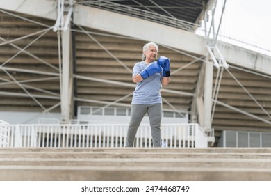 Asian senior sportswoman boxing while working out on parking outdoors - Powered by Shutterstock