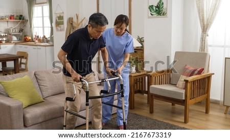 asian senior stroke patient undergoing rehab exercise with a walker at home. the woman nursing aide assists him during home visit