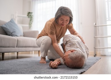 Asian senior wife helping husband fainting and falling on the ground in the living room. Elderly male patient having an accident or heart attack. home nursing and health insurance concept - Shutterstock ID 2172115153