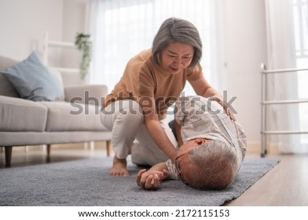 Asian senior wife helping husband fainting and falling on the ground in the living room. Elderly male patient having an accident or heart attack. home nursing and health insurance concept Сток-фото © 