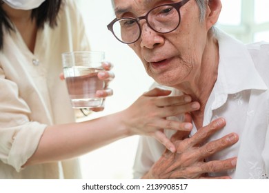 Asian senior woman coughing choking while drinking water or eating food,danger or risk of lung infection,disease of silent aspiration pneumonia,old elderly patient choking water after taking the pills - Shutterstock ID 2139908517
