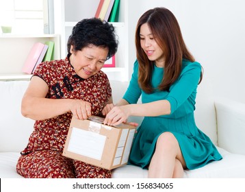 Asian Senior Woman And Daughter Opening A Courier Parcel