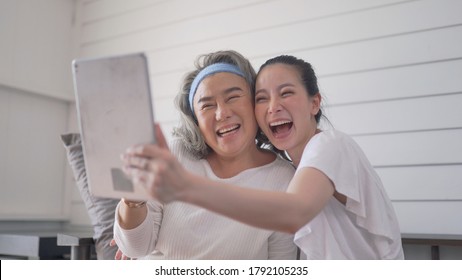 Asian senior woman and daughter video conferencing on tablet at home - Powered by Shutterstock