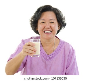 Asian Senior Woman Drinking A Glass Of Soy Milk Over White Background