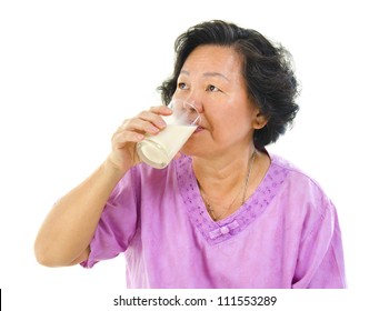 Asian Senior Woman Drinking A Glass Of Soy Milk Over White Background