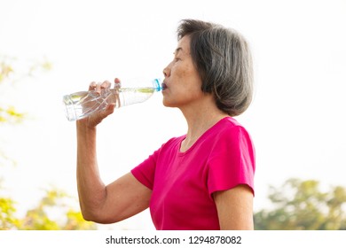 Asian Senior Woman Drinking Water From The Bottle.