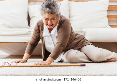 Asian senior woman falling down lying on floor at home alone. Elderly woman pain and hurt from osteoporosis sickness or heart attack. Old adult life insurance with hearlth care and treatment concept