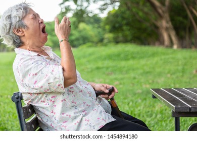 Asian senior woman has sleepy expression,elderly woman yawning covering open mouth with hand,old people feeling yawn,doze,sleepy in outdoor park,being tired after sleepless night,lack of sleep concept - Powered by Shutterstock