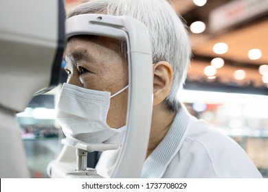 Asian senior woman having eyesight test using tonometer looking into the machine,old elderly patient checks her vision,eye examination by ophthalmlogist,presbyopia problems,health care at eye clinic