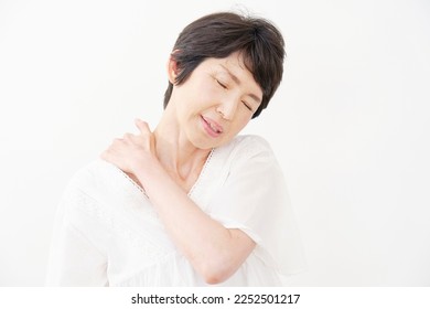 Asian senior woman having stiff shoulders in white background