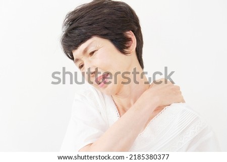 Asian senior woman having stiff shoulders in white background 