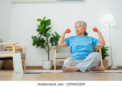 Asian Senior Woman Lifting Dumbbell For Exercise And Workout At Home. Active Mature Woman Doing Stretching Exercise In Living Room. Exercise Active And Healthy For Older, Elder, And Senior Concept.