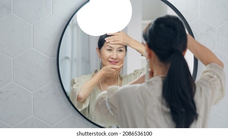 Asian Senior Woman Looking At A Mirror. Anti Aging. Skincare.