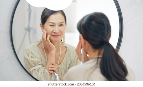 Asian Senior Woman Looking At A Mirror. Anti Aging. Skincare.