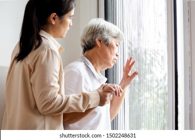 Asian Senior Woman Looking Through The Window In Bedroom,feeling Sad And Lost; Depressed Elderly People Waiting For His Family To Visit At Nursing Home,facial Expression,life Depression,nostalgia 