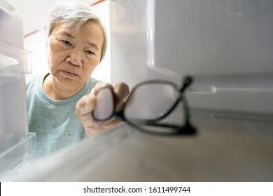 Asian Senior Woman With Memory Impairment Symptoms,forget Her Glasses In The Refrigerator Or Storing Glasses In The Fridge,female Elderly Having Dementia, Cognitive Impairment, Alzheimer's, Amnesia