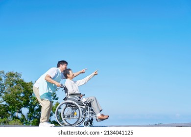 Asian Senior Woman On The Wheelchair And Asian Caregiver Outdoor