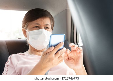 Asian Senior Woman Passenger Wear Surgical Mask For Prevent Coronavirus Or Covid-19 Using Smartphone While Sitting In Car. Pandemic Virus In Public Transportation.