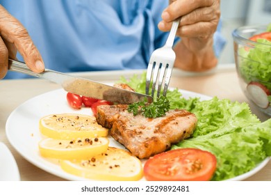 Asian senior woman patient eating pork chop stake and vegetable salad for healthy food in hospital. - Powered by Shutterstock