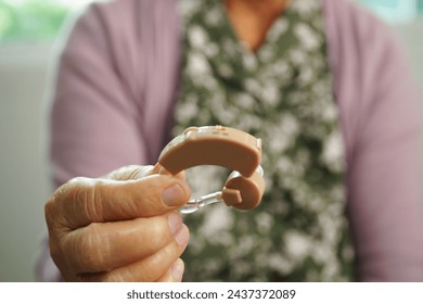 Asian senior woman patient using hearing aid in ear to reduce hearing loss problem. - Powered by Shutterstock