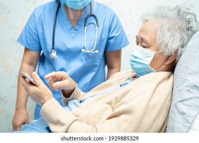 Asiatische ältere Patientin, die eine Gesichtsmaske trägt und ein Mobiltelefon im Krankenhaus hält, um die Sicherheitsinfektion Covid-19 Coronavirus zu schützen.