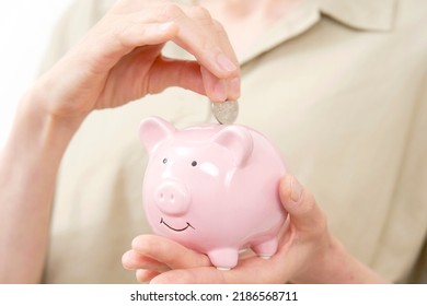 Asian Senior Woman Putting Coins In Piggy Bank, No Face