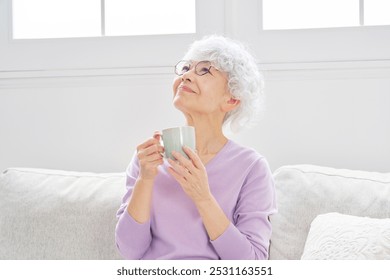 Asian senior woman relaxing with the mug in the living room - Powered by Shutterstock