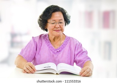 Asian Senior Woman Serious Reading Book At Home