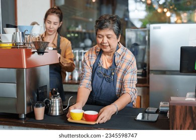 Asian senior woman Serving coffee to customers in front of bar counter In shop, beautiful Asian barista, owner's daughter, is preparing drinks by the side. Coffee machine page. family small business	
 - Powered by Shutterstock