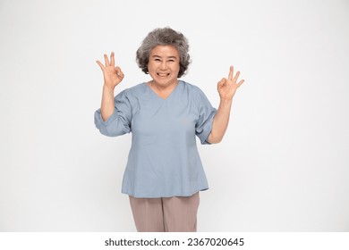 Asian senior woman smiling and showing OK sign isolated on white background - Powered by Shutterstock