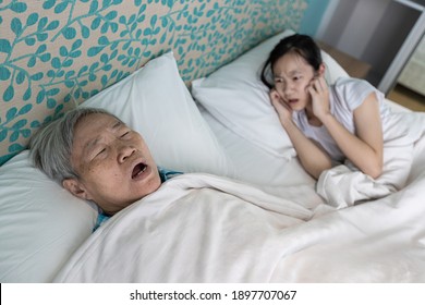 Asian Senior Woman Snoring Loudly,open Mouth,comfortably Sleeping,danger Of Obstructive Sleep Apnea Disease,stressed Child Girl Wakes Up,closing Ears With Hands,annoying Snoring Of Elderly People