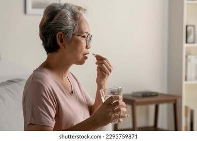 Asian senior woman taking medicine at home, age, medicine, healthcare and people concept - Powered by Shutterstock