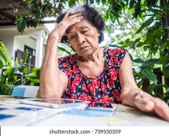 Asian Senior Woman Unhappy While Looking At Mobile Phone And Digital Tablet Abstract Loss In Profits Sitting In The Garden, Internet Social Media, Network