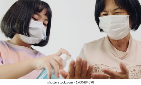 Asian senior woman using alcohol gel for hands washing with Asian girl together - Shutterstock ID 1700484598