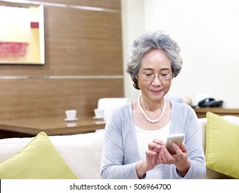 Asian Senior Woman Using Mobile Phone At Home